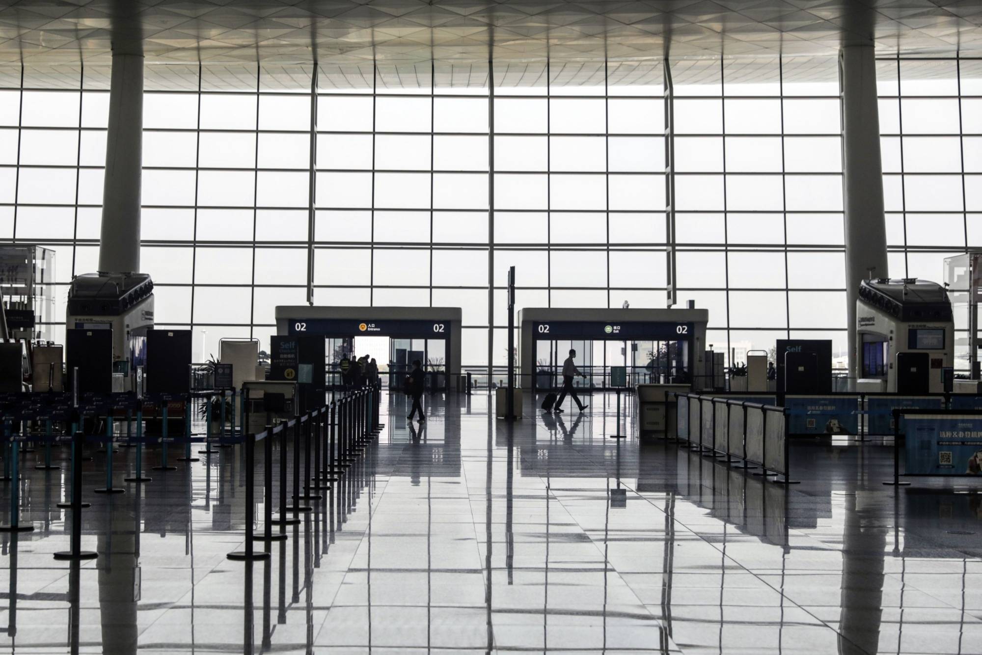 People walk through the near empty departure hall of the Wuhan Tianhe International Airport in Wuhan, China, on May 2. | BLOOMBERG