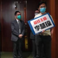 Pro-democracy lawmaker Eddie Chu holds a placard outside the chamber of the Legislative Council Complex after he was ejected minutes following a second-day legislative debate in Hong Kong on Thursday.  | AP