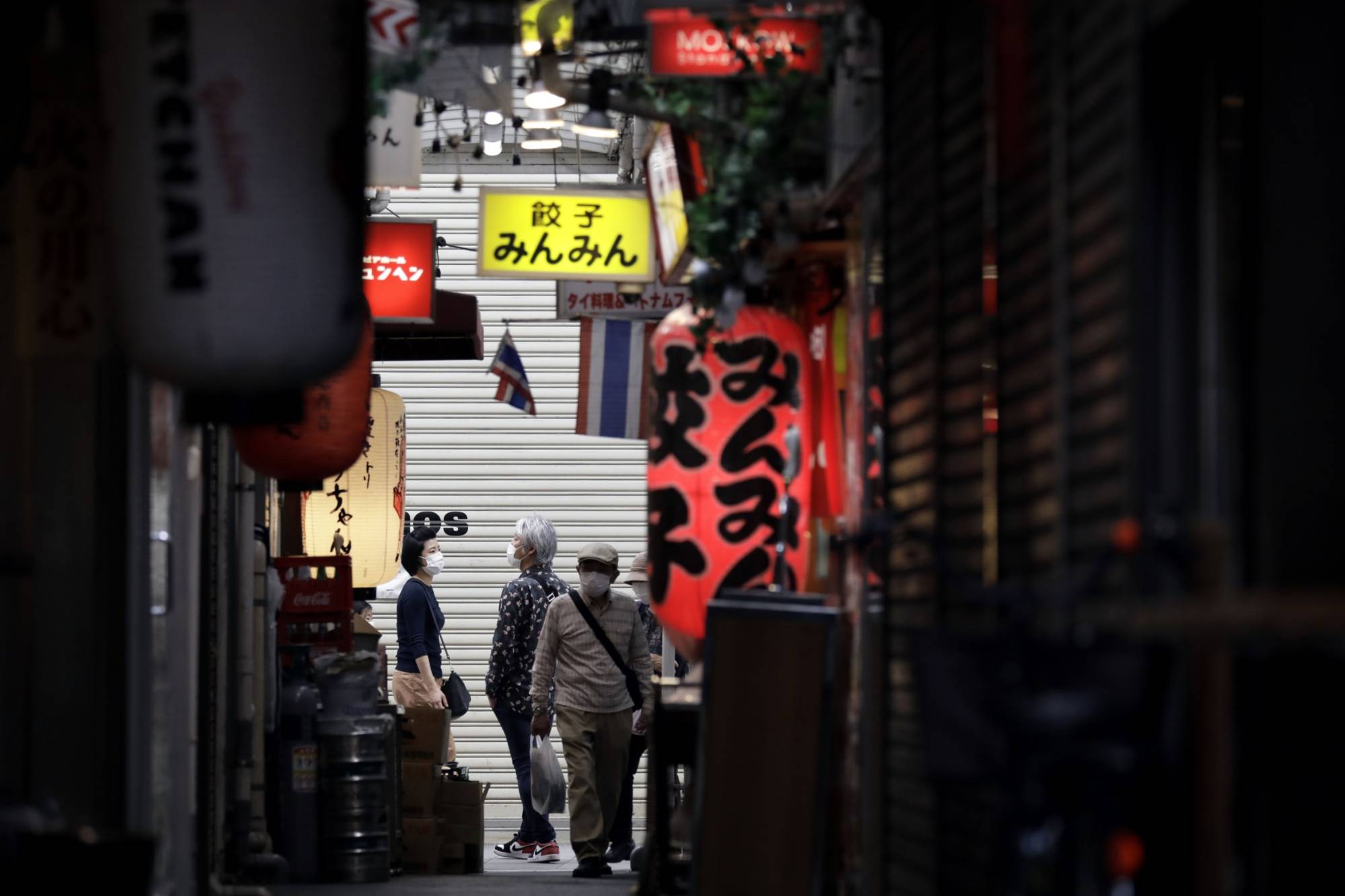Pedestrians wearing protective masks walk through a shopping street in the Kichijoji area of Tokyo on Tuesday.  | BLOOMBERG