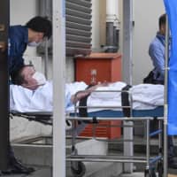 Shinji Aoba lies on a stretcher as he is brought into Fushimi Police Station in Kyoto on Wednesday after being arrested. | KYODO