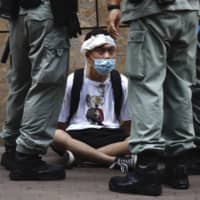 Riot police guard a protester on Wednesday in Hong Kong. Beijing’s decision to force national security laws on Hong Kong has outraged many in the European Union for what they see as an attack on democracy. | AP