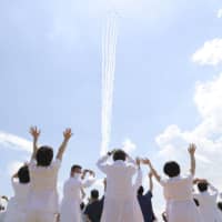 The Air Self-Defense Force\'s Blue Impulse acrobatics corps flies over Tokyo on Friday afternoon to express appreciation to medical workers on the frontlines fighting the COVID-19 pandemic, as medical staff of Self-Defense Forces Central Hospital in Setagaya Ward look at the performance. | KYODO