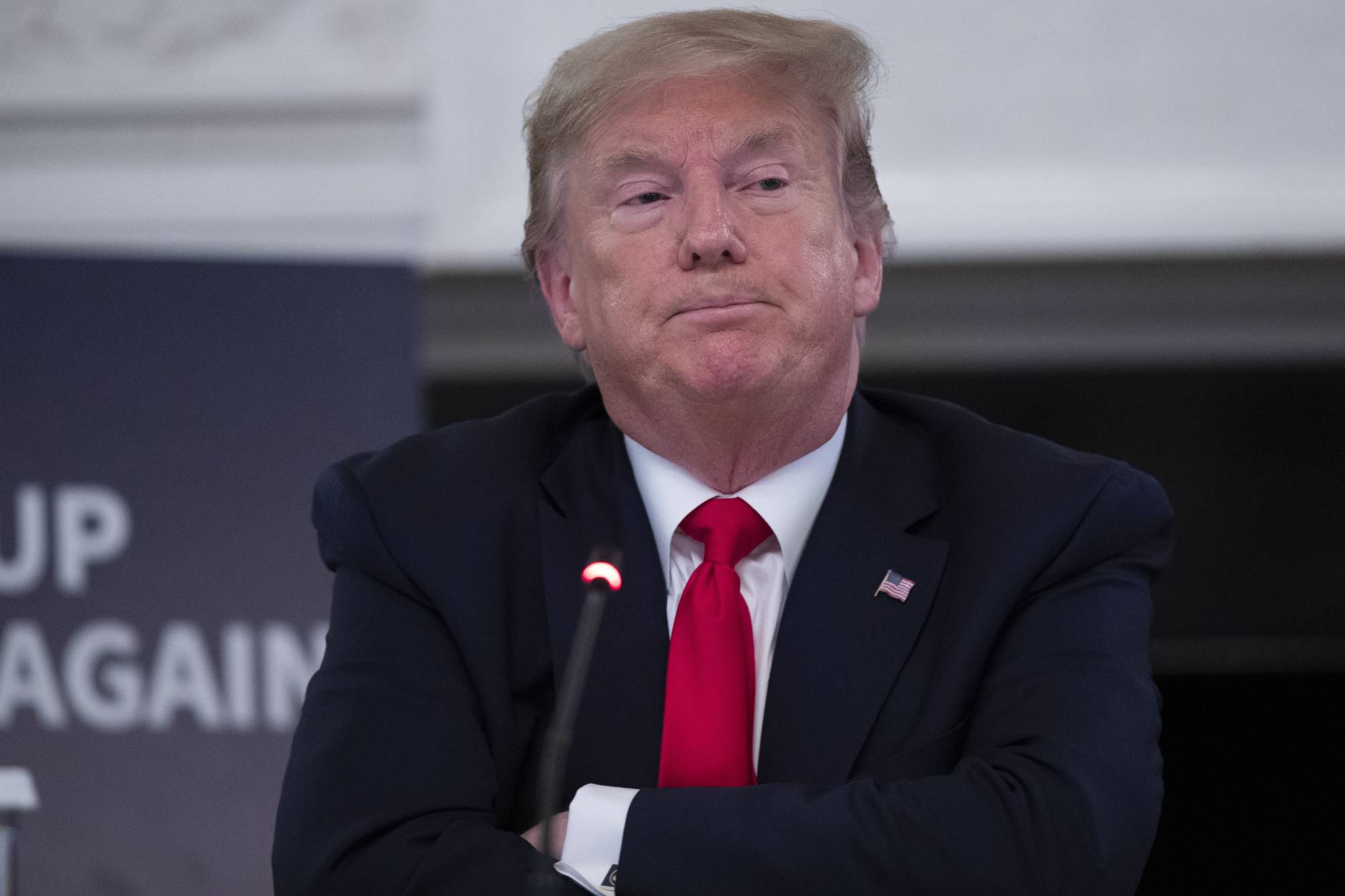 U.S. President Donald Trump folds his arms after speaking during a roundtable with industry executives about reopening the country after the coronavirus closures, in the State Dining Room of the White House in Washington, on Friday. | AP