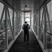 A passenger walks in a enclosed bridge to board his flight at Tianhe Airport in Wuhan, China, on Friday. | AFP-JIJI