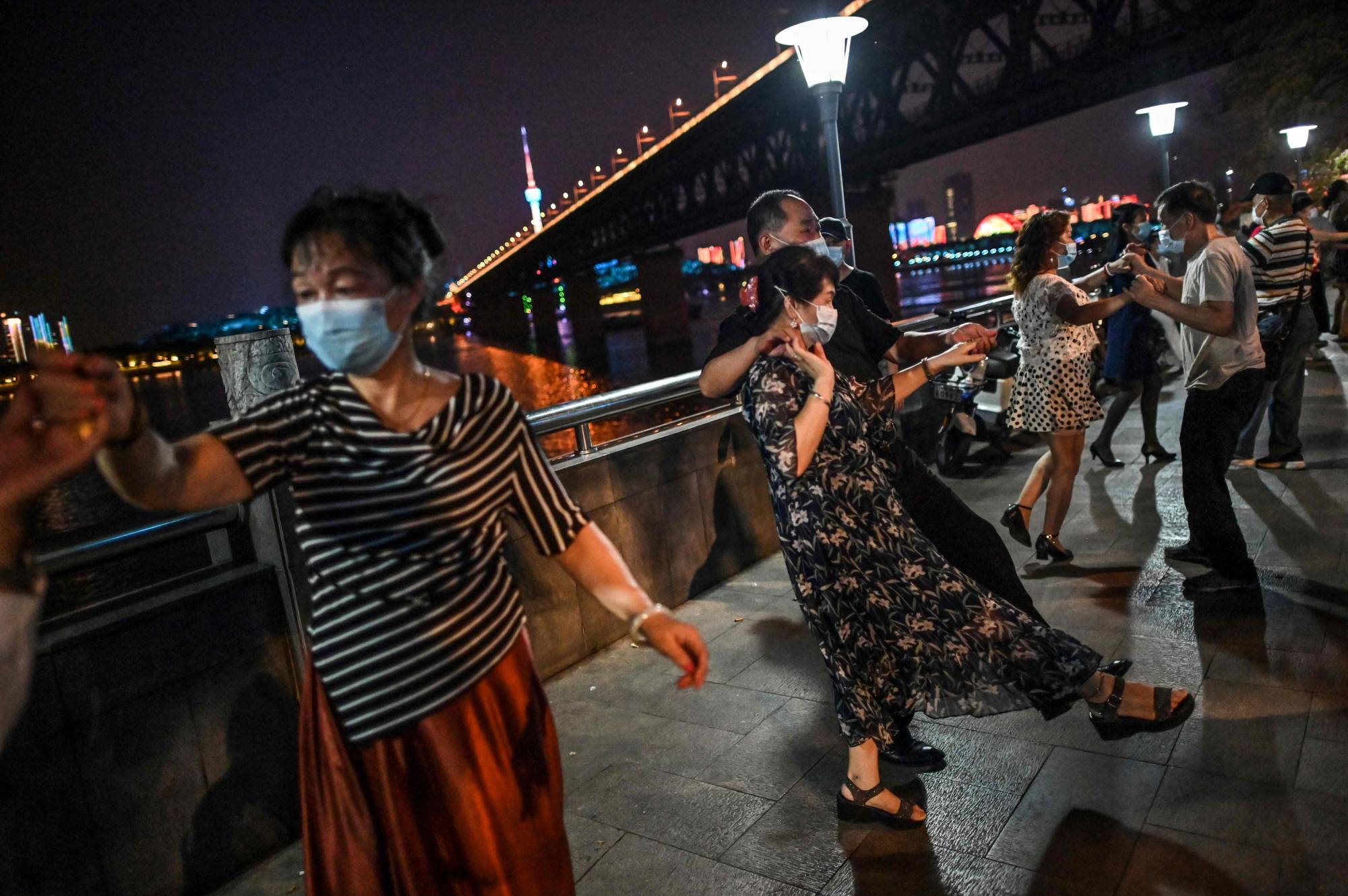 People wearing face masks dance in a park next to the Yangtze River in Wuhan, China, on Wednesday. | AFP-JIJI