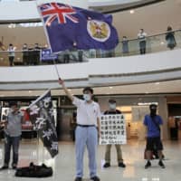 Protesters wave a Hong Kong colonial flag in a shopping mall during a protest against China\'s national security legislation for the city on Friday. The British government says it will grant nearly 3 million Hong Kong residents greater visa rights if China doesn\'t scrap a planned new security law for the semiautonomous territory.  | AP