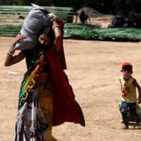 A migrant carries luggage on her head with her son following behind as they walk to reach a bus to take them to their home state of Uttar Pradesh, in Mumbai on Tuesday.  | REUTERS