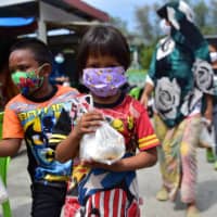 Children carry food donations in Thailand\'s southern province of Narathiwat on April 23. The Distance Learning Television program that was developed for learners in remote rural areas is now being extended nationwide with new courses being recorded to broaden the curriculum. | AFP-JIJI