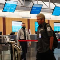 Workers wear protective masks at the American Airlines check-in area at San Diego International Airport on Monday. | BLOOMBERG