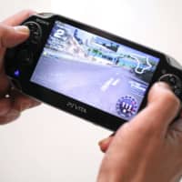 A man plays the game Ridgeracer on a Sony Corp.PlayStation Vita games console in London. | BLOOMBERG