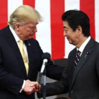 U.S. President Donald Trump shakes hands with Prime Minister Shinzo Abe during a speech to Japanese and U.S. troops aboard the Maritime Self-Defense Force\'s Kaga helicopter carrier at the Yokosuka naval base in Kanagawa Prefecture in May last year. | POOL / VIA REUTERS