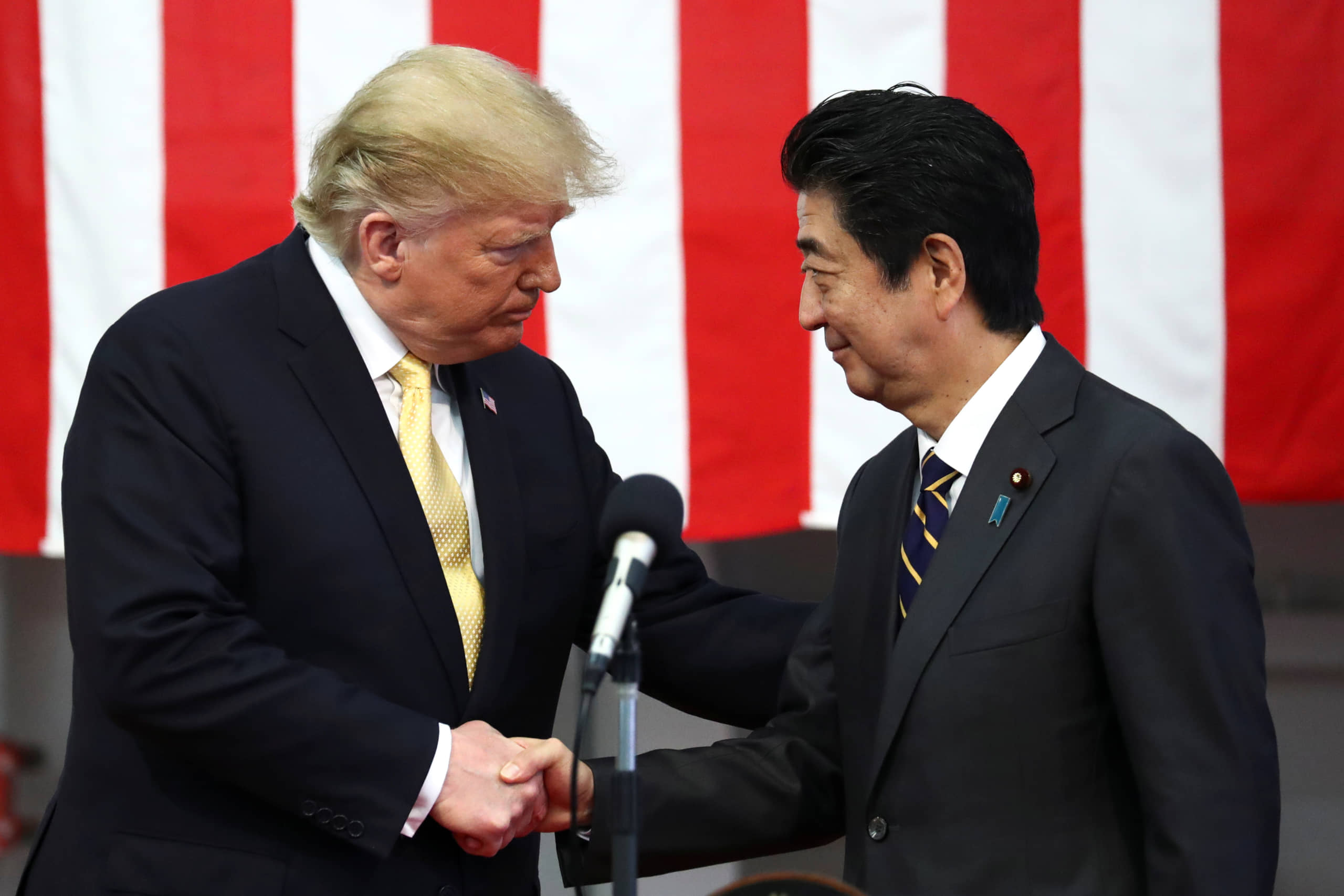 U.S. President Donald Trump shakes hands with Prime Minister Shinzo Abe during a speech to Japanese and U.S. troops aboard the Maritime Self-Defense Force's Kaga helicopter carrier at the Yokosuka naval base in Kanagawa Prefecture in May last year. | POOL / VIA REUTERS