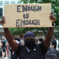 A protester holds up a sign in Tokyo’s Shibuya Ward on Saturday as part of rallies to speak out against police brutality and the treatment of foreign residents in Japan. | RYUSEI TAKAHASHI