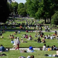 People relax in Paris\' Jardin de Montsouris park on Sunday, the second day of reopening following the nationwide lockdown put into place on March 17 to in response to the coronavirus outbreak. | AFP-JIJI