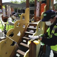 Quarantine officials disinfect a park as a precaution against the new coronavirus in Gunpo, South Korea, on Monday. | YONHAP / VIA AP