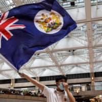 A pro-democracy protester waves a British colonial flag during a rally at a shopping mall in the Central district in Hong Kong on Monday. | AFP-JIJI