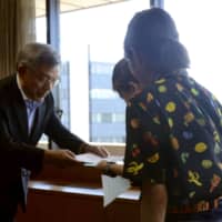 An LGBT couple receives a certificate recognizing their partnership from the deputy mayor of Kumamoto last August. | KYODO
