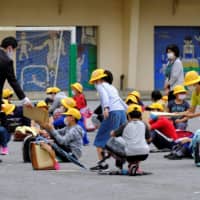 Elementary school students gather for a class in a schoolyard at a reopened school in Tokyo on Monday, a week after the government lifted the state of emergency nationwide. | AFP-JIJI
