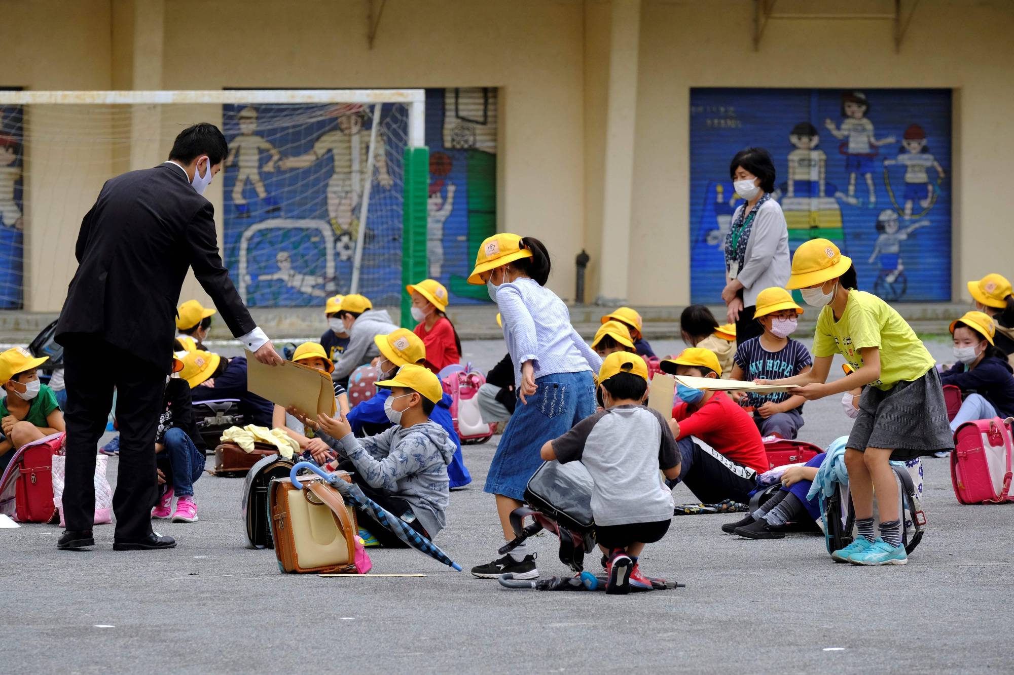 Elementary school students gather for a class in a schoolyard at a reopened school in Tokyo on Monday, a week after the government lifted the state of emergency nationwide. | AFP-JIJI