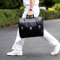 A military aide carries a briefcase containing launch codes for nuclear weapons as U.S. President Donald Trump returns to the White House in Washington in July 2018. | REUTERS