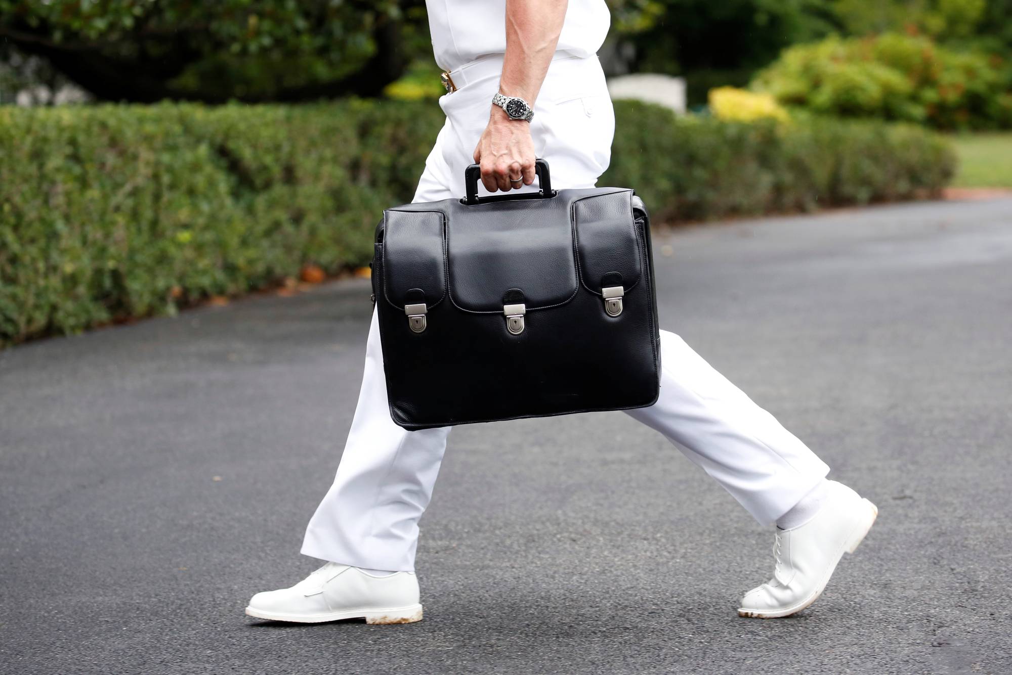 A military aide carries a briefcase containing launch codes for nuclear weapons as U.S. President Donald Trump returns to the White House in Washington in July 2018. | REUTERS