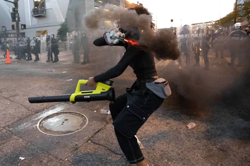 A protester in Atlanta throws a smoke device at police during a protest over the death of George Floyd, who died while in police custody last week in Minneapolis. | AP