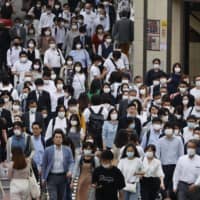 People wearing masks walk near Shinjuku Station on Tuesday. | KYODO