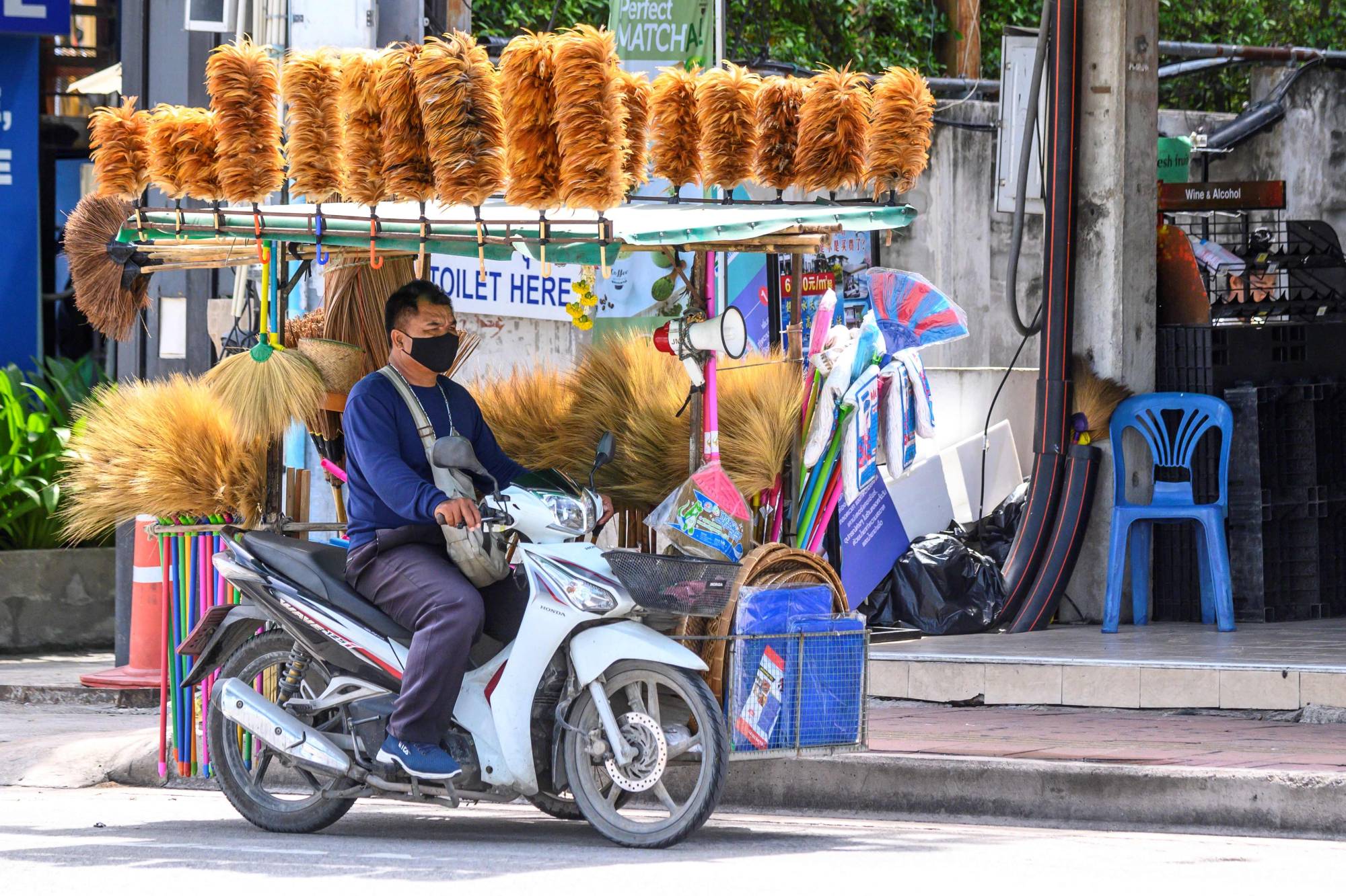 A vendor sells brooms and dusters from his motorbike in Pattaya, Thailand, on Monday. | AFP-JIJI