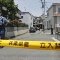 A police office stands guard near the house where two women were killed by arrows in Takarazuka, Hyogo Prefecture, on Thursday. | KYODO