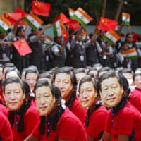 Students wear masks of Chinese President Xi Jinping as others wave Indian and Chinese flags, ahead of an informal summit between Xi and Indian Prime Minister Narendra Modi, at a school in Chennai, India, in October. Analysts say Modi risks stoking tensions with Beijing in siding too closely with Donald Trump. | REUTERS