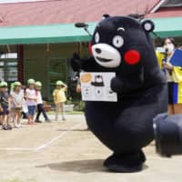 Kumamon calls on children to wash their hands during a surprise visit to a nursery school in Kosa, Kumamoto Prefecture, on Friday. | KYODO