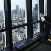 A man wearing a protective mask looks outside from the observation deck of Tokyo Tower.
 | AP