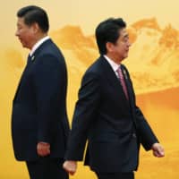 Prime Minister Shinzo Abe walks past Chinese leader Xi Jinping during a welcoming ceremony of the Asia Pacific Economic Cooperation forum, inside the International Convention Center at Yanqi Lake, Beijing, in November 2014. | REUTERS