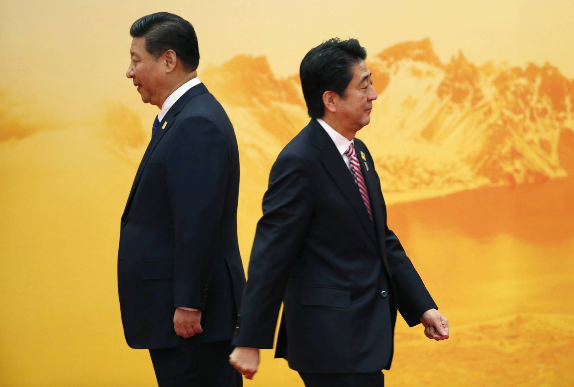 Prime Minister Shinzo Abe walks past Chinese leader Xi Jinping during a welcoming ceremony of the Asia Pacific Economic Cooperation forum, inside the International Convention Center at Yanqi Lake, Beijing, in November 2014. | REUTERS