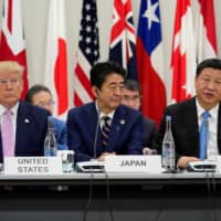 Prime Minister Shinzo Abe is flanked by U.S. President Donald Trump and Chinese leader Xi Jinping during a meeting at the Group of 20 summit in Osaka in June last year. | REUTERS