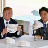 U.S. President Donald Trump Prime Minister Shinzo Abe pose after they signed and exchanged hats reading \"Donald and Shinzo, Make Alliance Even Greater\" at the Kasumigaseki Country Club in Kawagoe, Saitama Prefecture, in November 2017. | POOL / VIA REUTERS