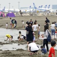 People play at a seaside park in Tokyo on Saturday near the Haneda airport. | KYODO