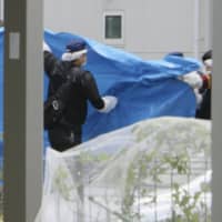 Metropolitan Police Department officers conduct an investigation in a residential area in Hachioji, Tokyo, on Monday. | KYODO