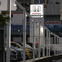 Used Honda Motor Co. vehicles are displayed at a dealership in Tokyo at night on May 10. | BLOOMBERG