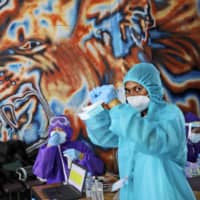 Health workers wait to collect blood samples during a large-scale testing operation for the new coronavirus in Jakarta, Indonesia, on Monday.  | AP