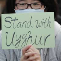 A man holds a sign during a rally to show support for Uighurs and their fight for human rights, in Hong Kong in December. | AP