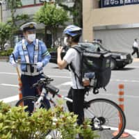 A police officer warns a cyclist for dangerous cycling in Tokyo on Friday. | KYODO
