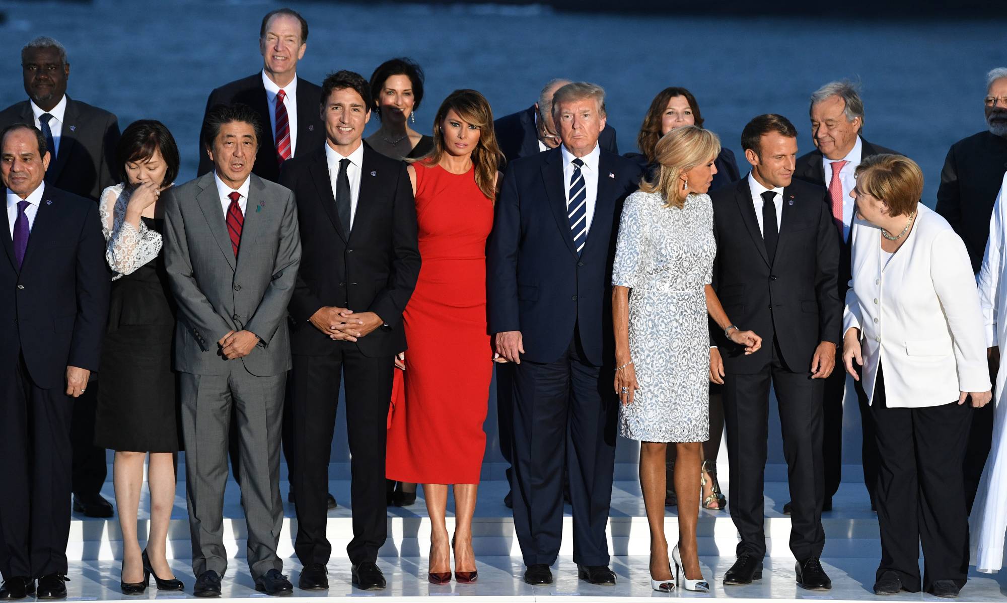 French President Emmanuel Macron and his wife, Brigitte Macron, U.S. President Donald Trump and First Lady Melania Trump, Prime Minister Shinzo Abe, Canadaian Prime Minister Justin Trudeau and German Chancellor Angela Merkel pose for a photo with guests during the G7 summit in Biarritz, France, on Aug. 25. | POOL / VIA REUTERS