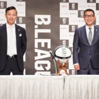 Incoming B. League Chairman Shinji Shimada (left) and Masaaki Okawa, the current league chairman, pose for photos during a news conference on Wednesday. | B. LEAGUE