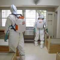 Officers disinfect a cell at Kyoto Prison on Friday as part of a drill to prepare for a possible COVID-19 outbreak at a jail facility. | KYODO