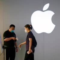 A woman wearing a protective face mask waits to measure her temperature in an Apple Store in Shanghai on Monday. | REUTERS