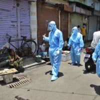 Doctors ask roadside vendors in Dharavi to wear masks. | AP