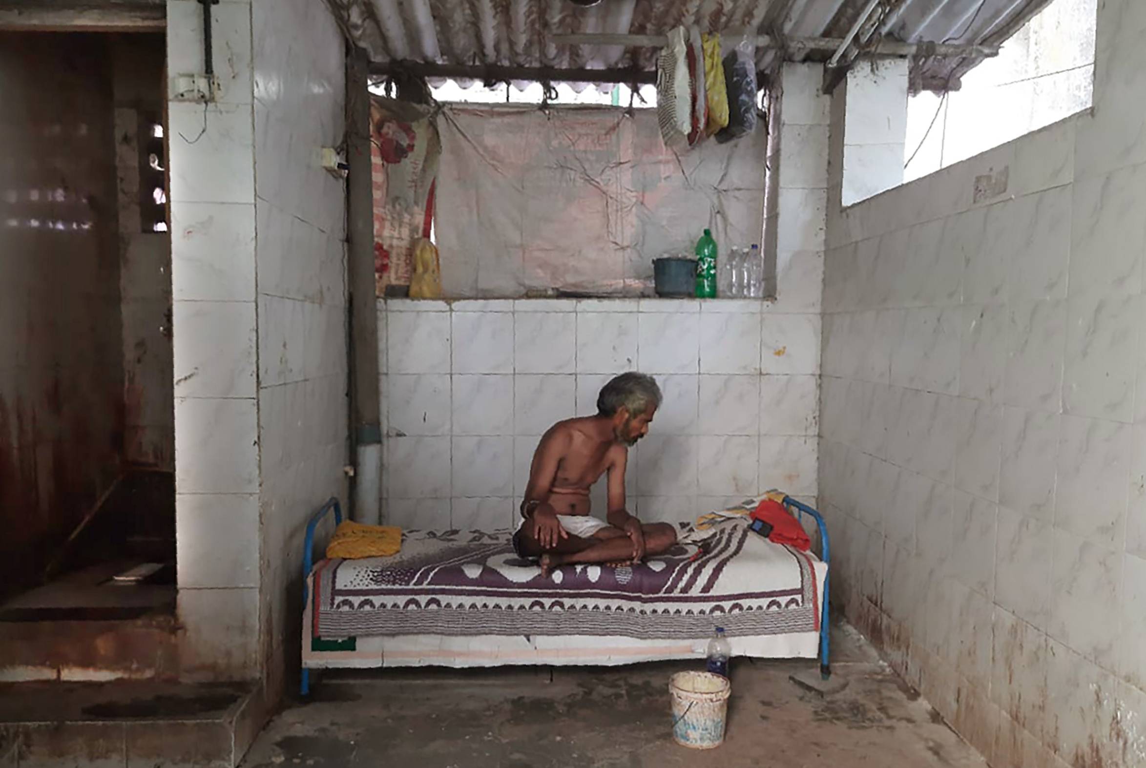 A man rests on his bed in Dharavi, one of Asia's largest slums. | Kunal Kanase / via AP