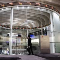 A man takes a photograph as an electronic ticker displays share prices at the Tokyo Stock Exchange, operated by Japan Exchange Group Inc., in Tokyo in April 2019. The IPO dry spell caused by the coronavirus rivals the one that followed the 2011 earthquake, when there were no listings in Japan for 77 days between March and June. | BLOOMBERG
