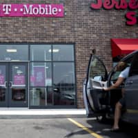 A person exits a vehicle in front of a T-Mobile U.S. Inc. store in Peru, Illinois, last July. SoftBank Group Corp. said it is considering the sale of its T-Mobile U.S. Inc. shares. | BLOOMBERG